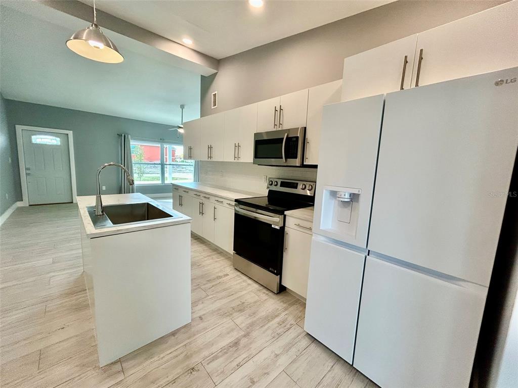 3112 Magnolia Way Punta Gorda, FL 33950 - Photo 6 of 20 a kitchen with stainless steel appliances a refrigerator stove a sink and white cabinets