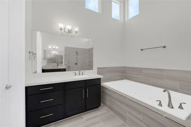 a bathroom with a bathtub a double vanity sink and mirror