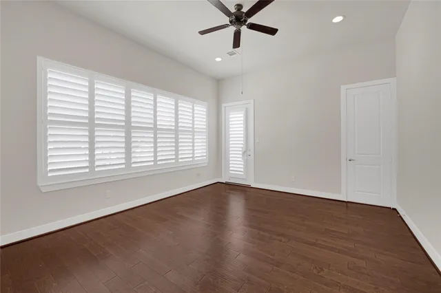an empty room with wooden floor fan and windows
