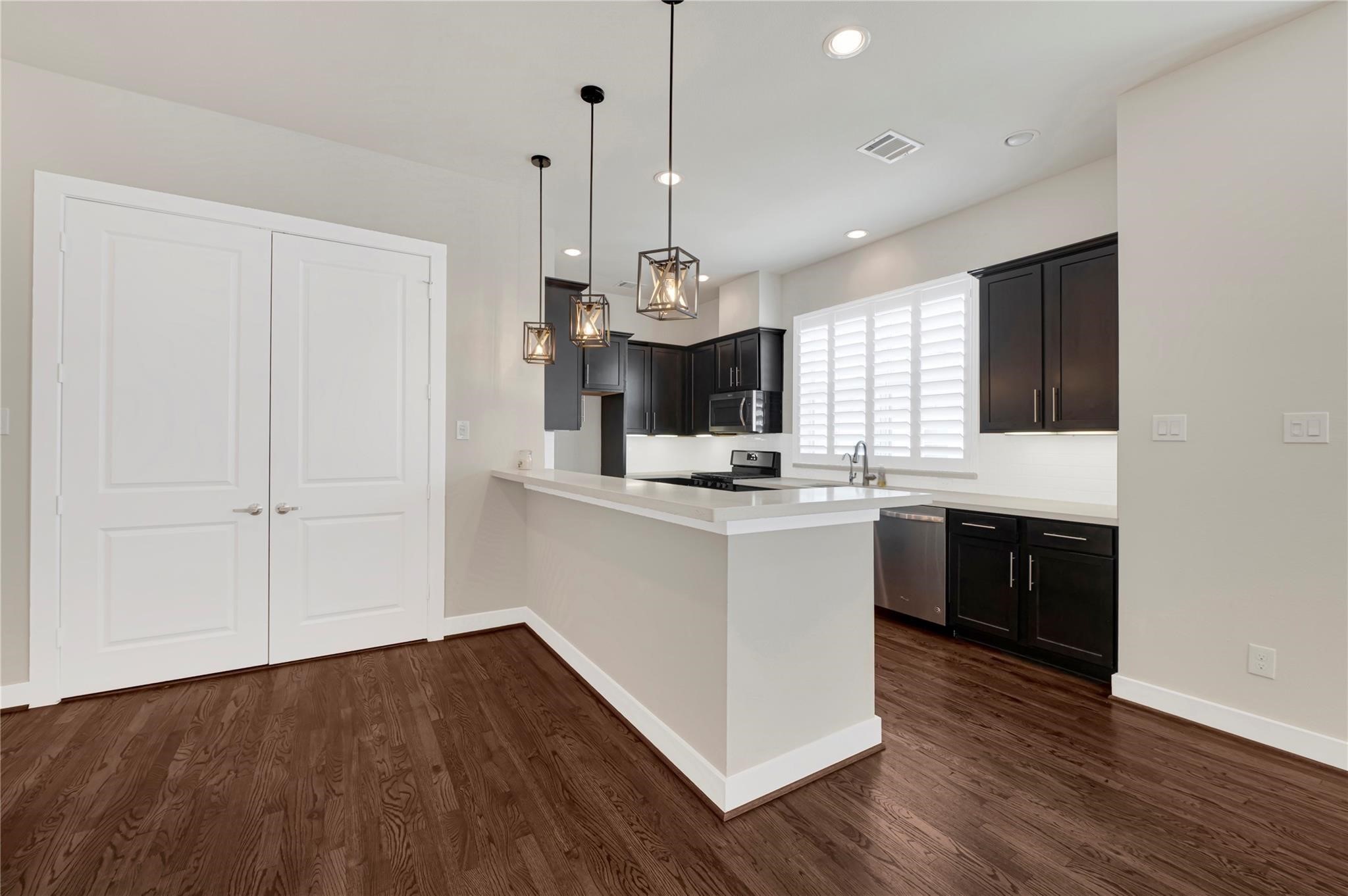 1210 Cedarpost Tree Springs Place, Unit P Houston, TX 77055 - Photo 7 of 25 a kitchen with kitchen island granite countertop wooden floors and white cabinets