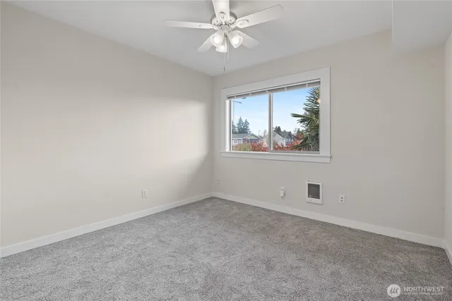 an empty room with a window and a fan