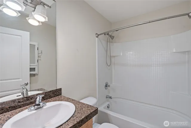 a bathroom with a granite countertop sink a mirror and a bathtub