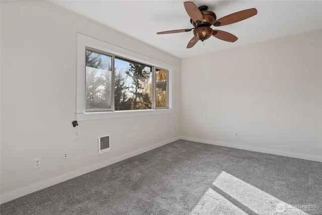 an empty room with a window and a fan