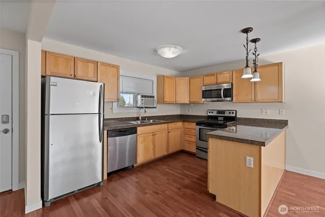 a kitchen with stainless steel appliances granite countertop a refrigerator a stove a sink dishwasher a microwave oven with cabinets and wooden floor