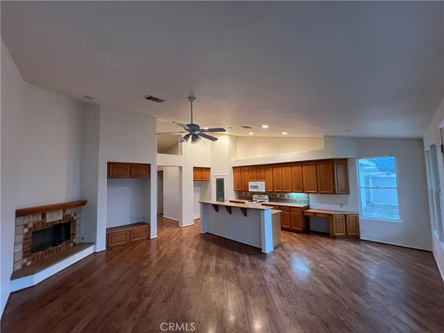 a living room with stainless steel appliances kitchen island wooden floors and fireplace
