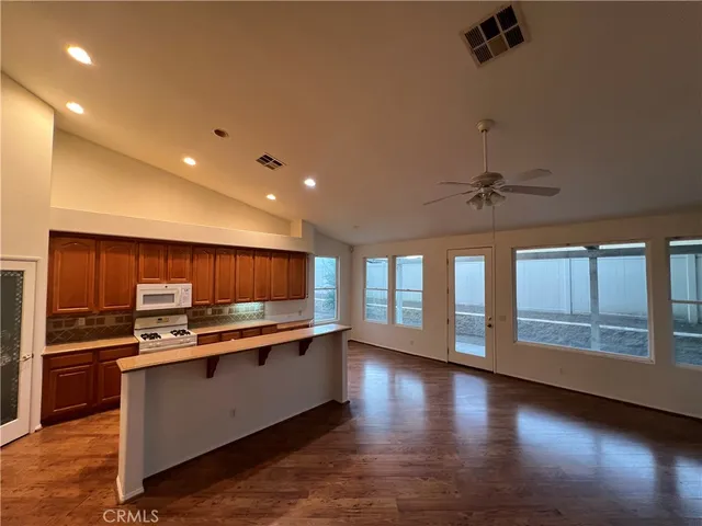 a kitchen with stainless steel appliances kitchen island granite countertop a stove a refrigerator and a microwave with wooden floor