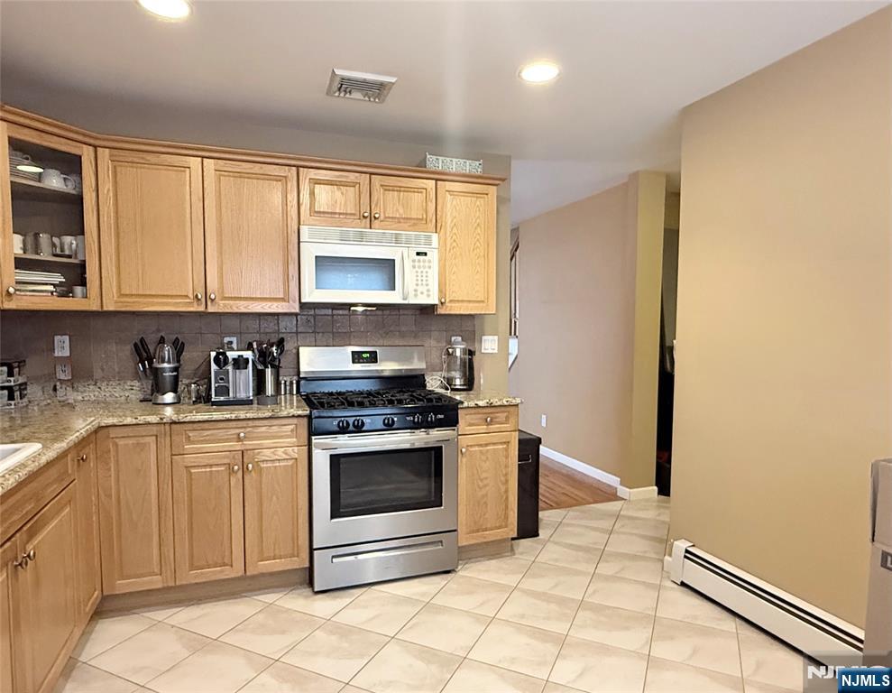 58 River Street, Unit B Lodi, NJ 07644 - Photo 8 of 11 a kitchen with granite countertop a stove top oven microwave and cabinets