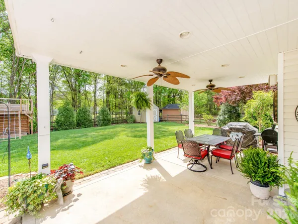 a view of a patio with table and chairs potted plants with wooden floor and fence