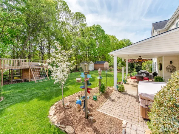 a view of a patio with table and chairs potted plants and large tree