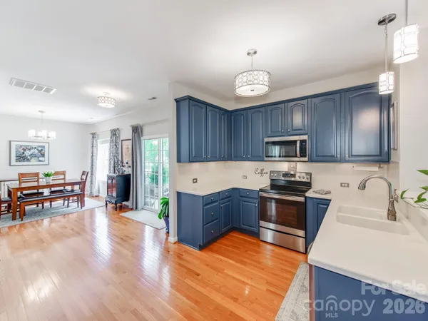 a large kitchen with stainless steel appliances granite countertop a stove and a wooden floors
