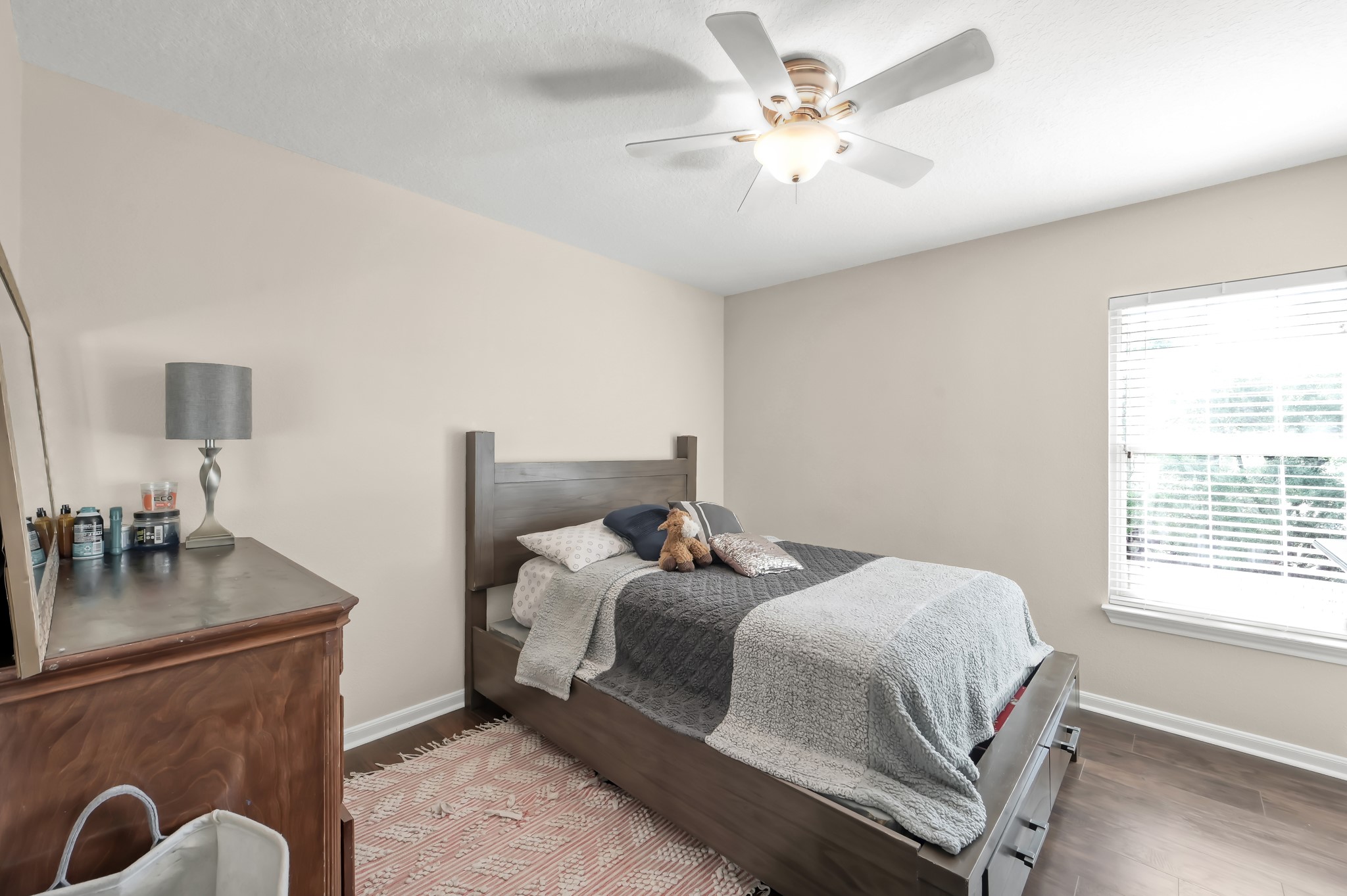 1000 Arbor Way Conroe, TX 77303 - Photo 22 of 29 This cozy bedroom features a neutral color palette, beautiful flooring, and a ceiling fan. It has a large window allowing natural light.