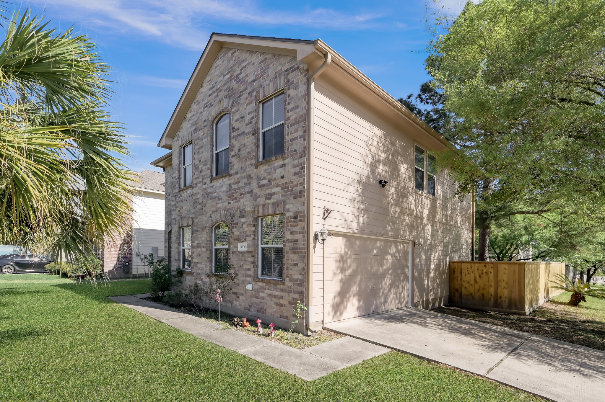 1000 Arbor Way Conroe, TX 77303 - Photo 3 of 29 Features an attached 2 car garage. The property has a well-maintained lawn, mature trees, and a wooden fence, offering a blend of privacy and curb appeal.