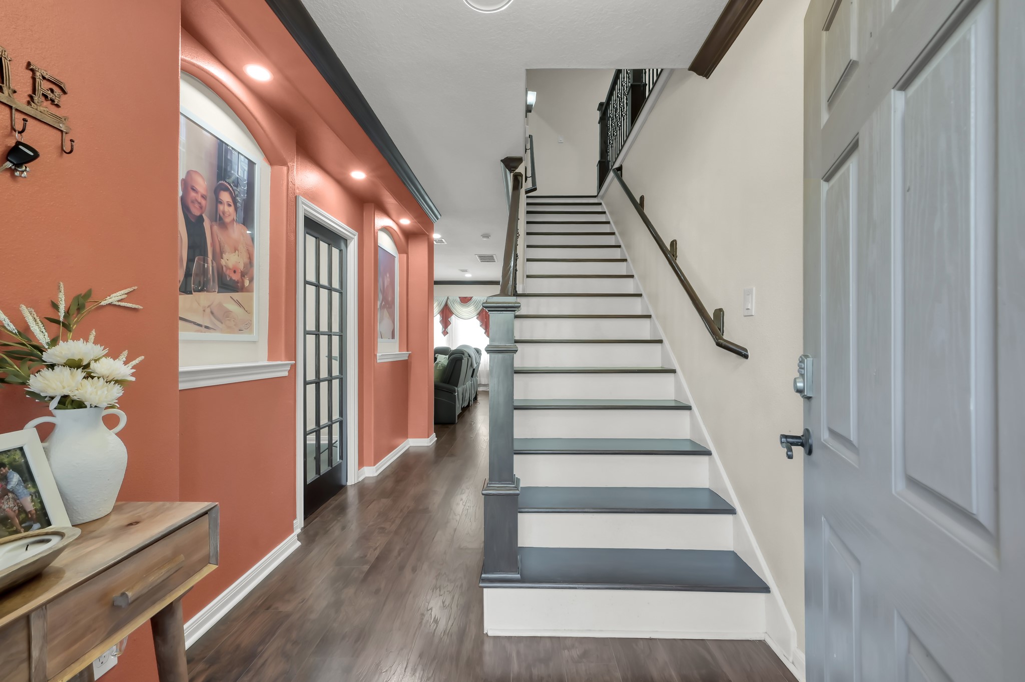 1000 Arbor Way Conroe, TX 77303 - Photo 4 of 29 A welcoming entryway with a well designed staircase. The space features warm color accent walls, recessed lighting, and luxury vinyl plan floors.