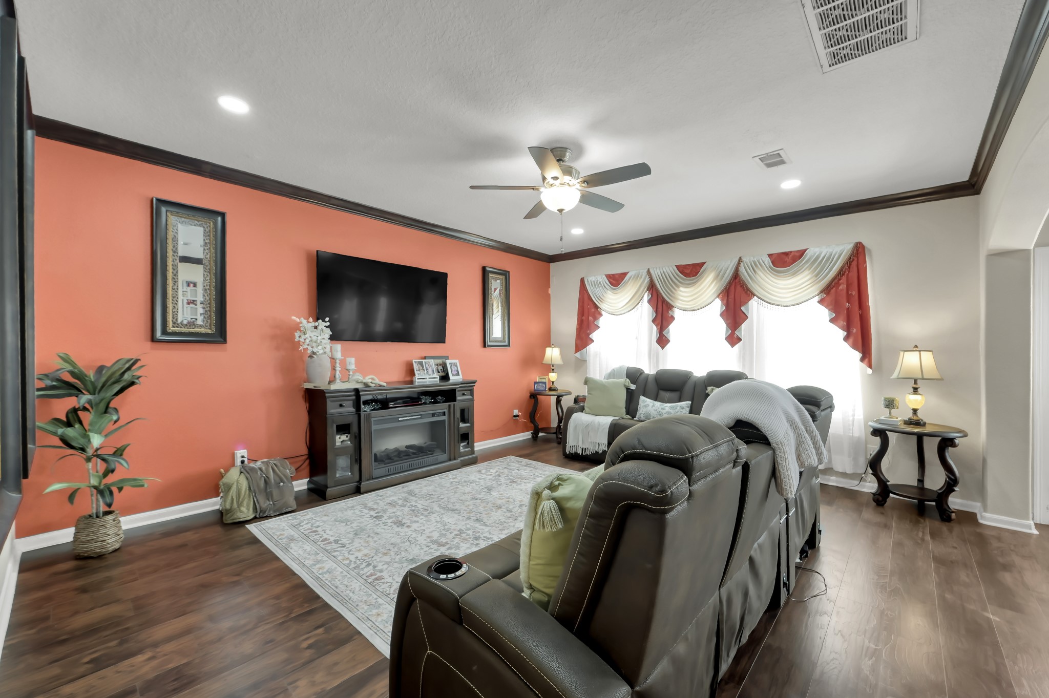 1000 Arbor Way Conroe, TX 77303 - Photo 6 of 29 This spacious living room features a warm color palette with an accent wall, luxury vinyl plan floors, and ample natural light creating an inviting space for relaxation and entertainment. Fireplace NOT included.
