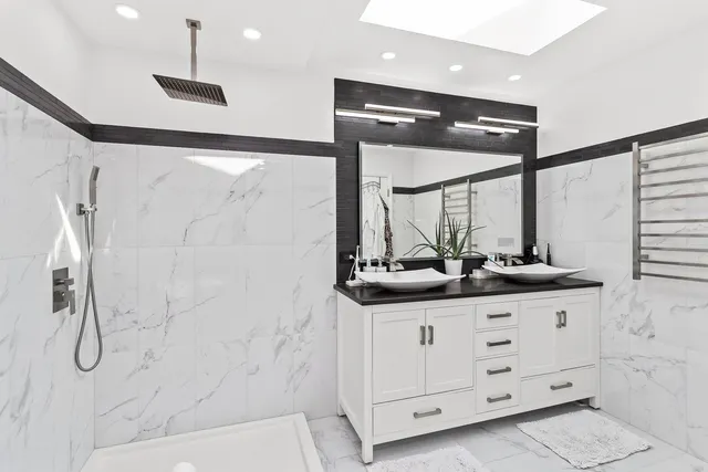 a bathroom with a double vanity sink a large mirror and shower