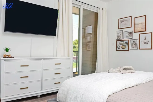 a bedroom with a bed and a flat tv screen on the dresser