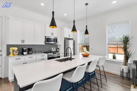 a kitchen with stainless steel appliances a dining table chairs a microwave a stove and a cabinets