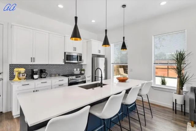 a kitchen with stainless steel appliances a dining table chairs a microwave a stove and a cabinets