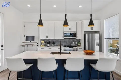 a kitchen with stainless steel appliances kitchen island granite countertop a sink a microwave a refrigerator and white cabinets