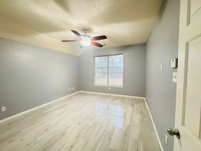 an empty room with windows and fan