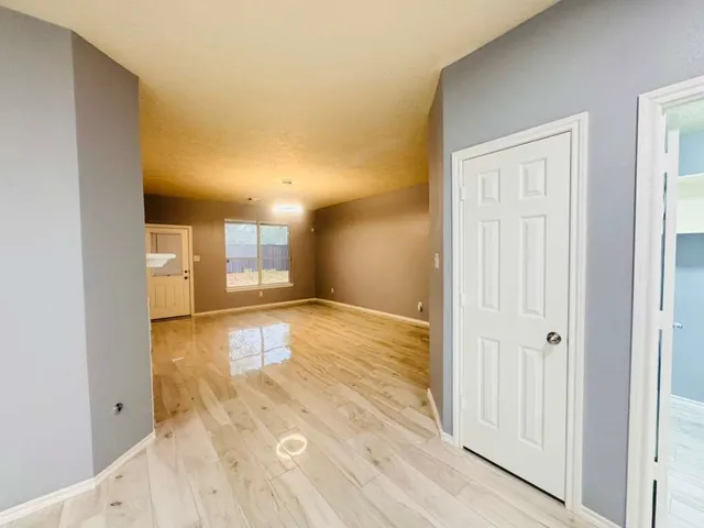 a view of a hallway with wooden floor and a bathroom