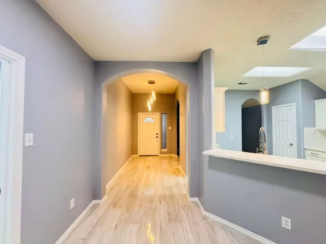 a view of a hallway with wooden floor and a bathroom