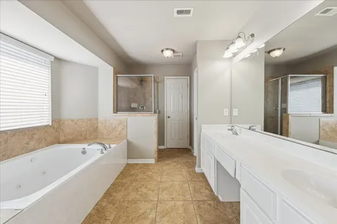 a large spacious bathroom with a tub sink shower and mirror