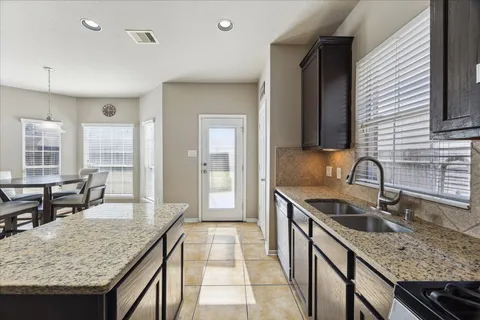 a kitchen with granite countertop kitchen island stainless steel appliances a sink stove and cabinets