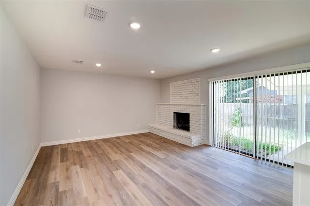 a view of empty room with wooden floor and fireplace