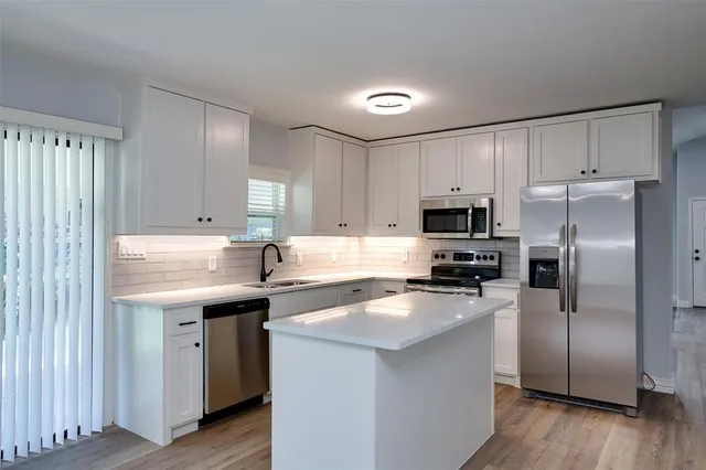 a kitchen with a sink a stove a refrigerator a center island and a window