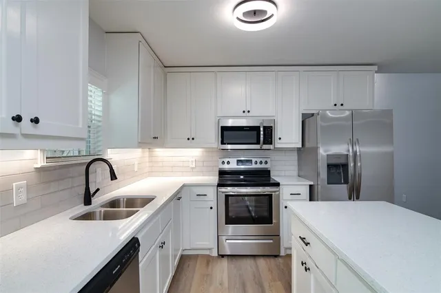 a kitchen with white cabinets and stainless steel appliances