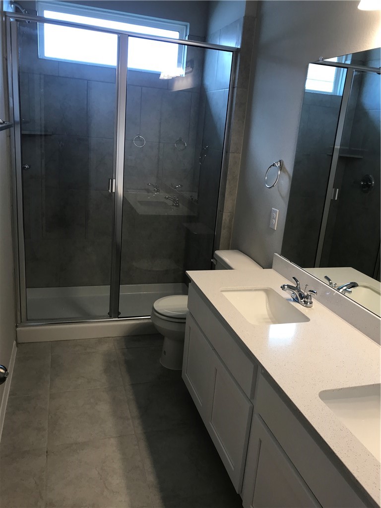 1353 Goforth Road Kyle, TX 78640 - Photo 17 of 24 a bathroom with a double vanity sink toilet and shower
