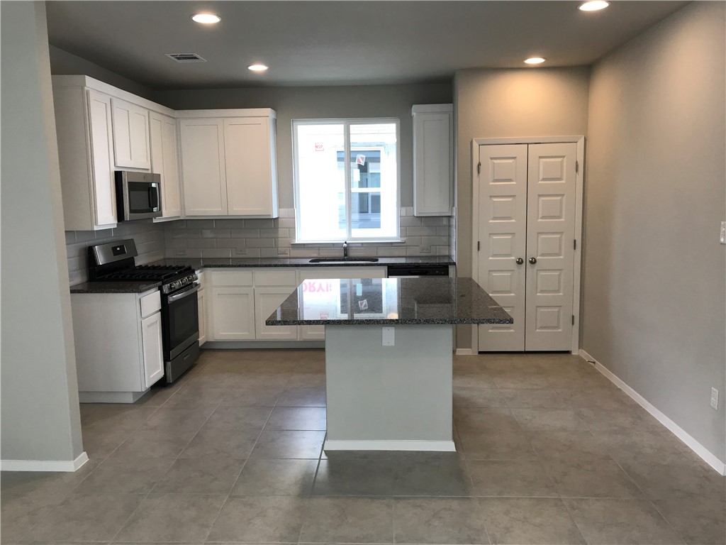 1353 Goforth Road Kyle, TX 78640 - Photo 6 of 24 a kitchen with stainless steel appliances granite countertop a stove a sink and a microwave