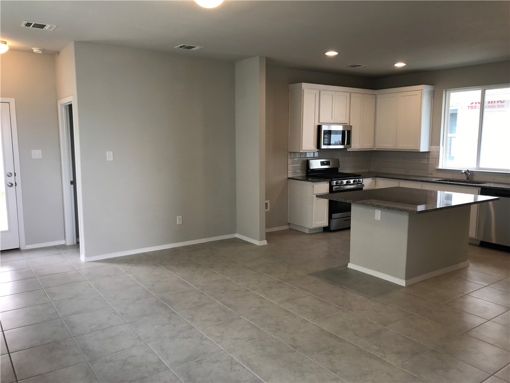 1353 Goforth Road Kyle, TX 78640 - Photo 8 of 24 a kitchen with stainless steel appliances granite countertop a stove a sink and a refrigerator