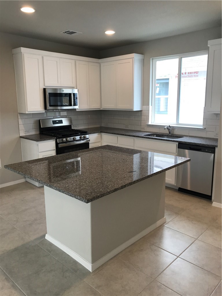 1353 Goforth Road Kyle, TX 78640 - Photo 10 of 24 a kitchen with stainless steel appliances granite countertop a sink counter space cabinets and a large window