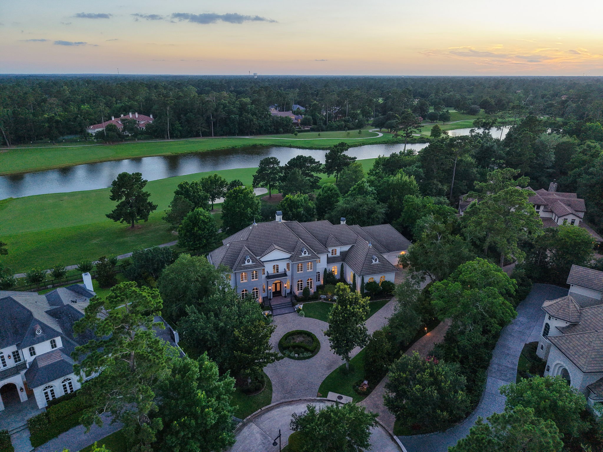 39 Maymont Way Spring, TX 77382 - Photo 3 of 50 This aerial photo showcases a luxurious estate set in a lush, wooded area with a scenic water feature and golf course in the background. The grand home features a stately entrance and well-manicured landscaping, offering privacy and elegance in a serene neighborhood.