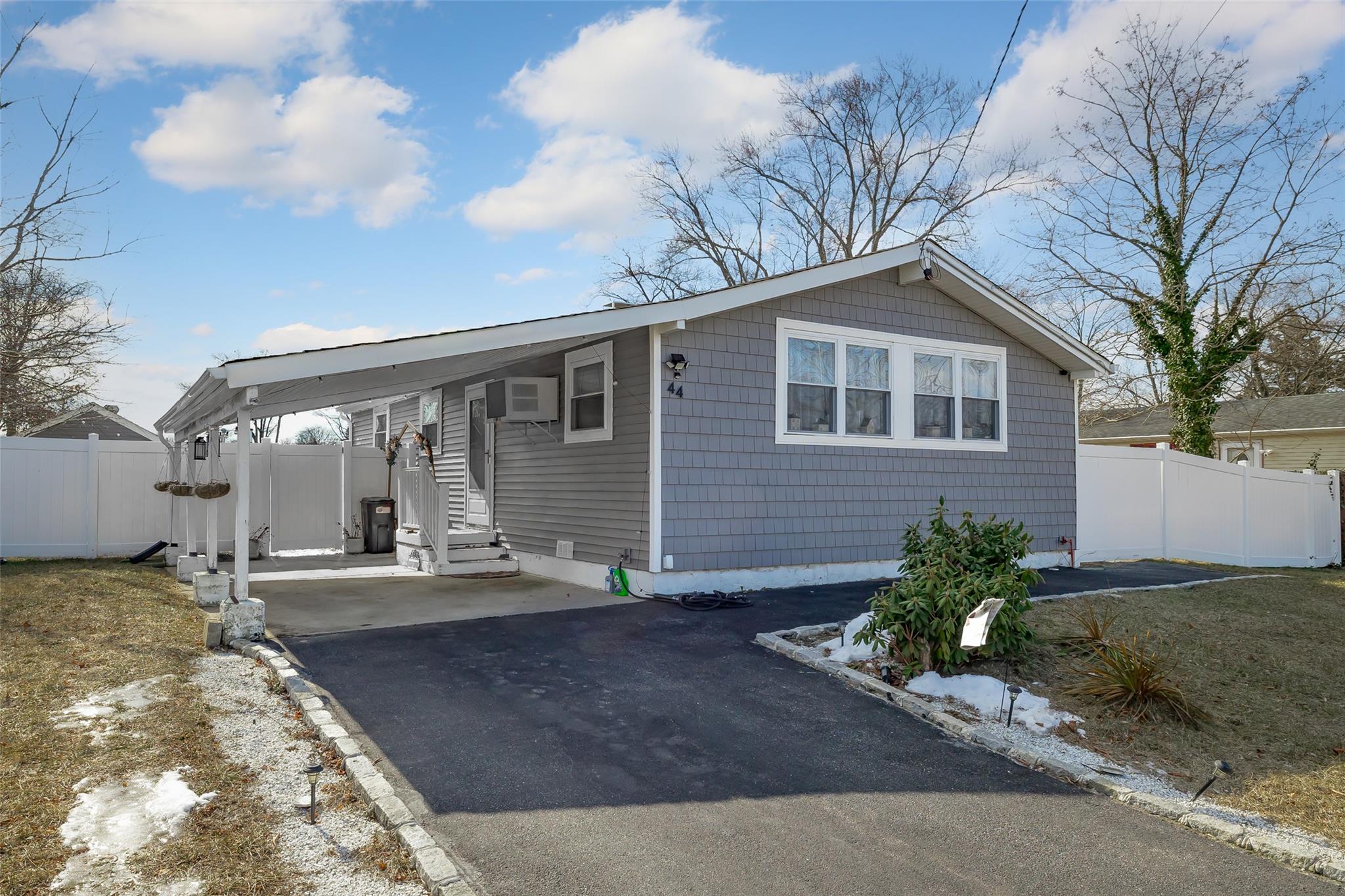 View of front of property with a wall mounted AC and a carport