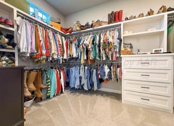 a view of walk in closet with clothes and shoes