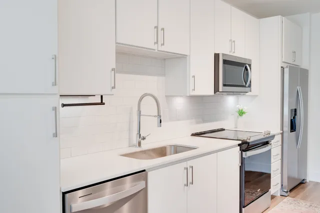 a kitchen with stainless steel appliances a sink dishwasher a refrigerator and cabinets