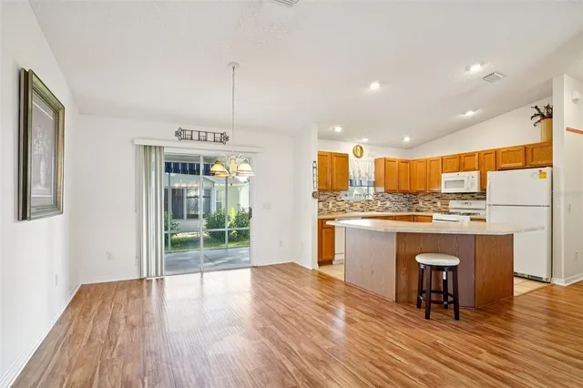 a large kitchen with granite countertop a stove top oven a sink and white cabinets with wooden floor