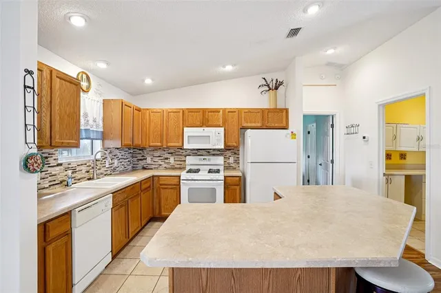 a kitchen with stainless steel appliances granite countertop a refrigerator a stove top oven a sink a dining table and chairs