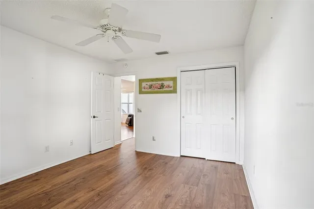 an empty room with wooden floor and ceiling fan