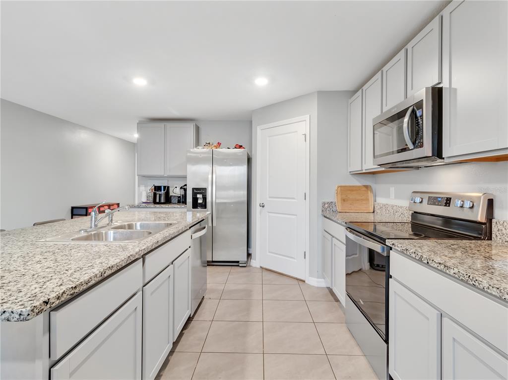 16636 Windmill Forge Pass Wimauma, FL 33598 - Photo 17 of 51 a kitchen with stainless steel appliances granite countertop a sink stove and refrigerator