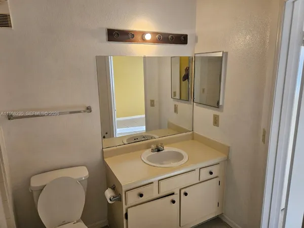 a bathroom with a toilet sink vanity granite and mirror