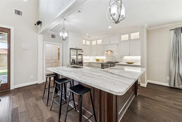 a dining hall with stainless steel appliances kitchen island granite countertop a dining table chairs and wooden floor