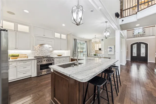 a kitchen with granite countertop a stove a sink a kitchen island with wooden floor and cabinets