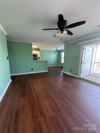an empty room with wooden floor a ceiling fan and windows