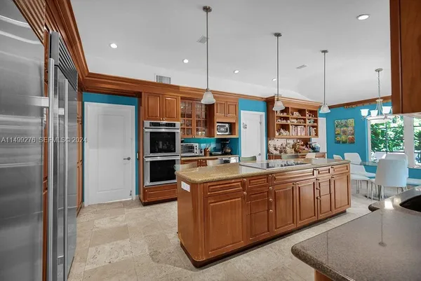 a kitchen with kitchen island granite countertop a sink and refrigerator