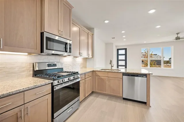 a kitchen with stainless steel appliances granite countertop a stove a sink and a microwave
