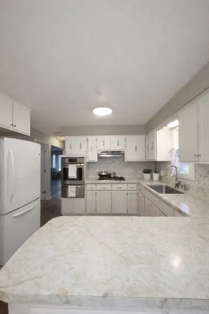 a kitchen with stainless steel appliances granite countertop a refrigerator sink and white cabinets